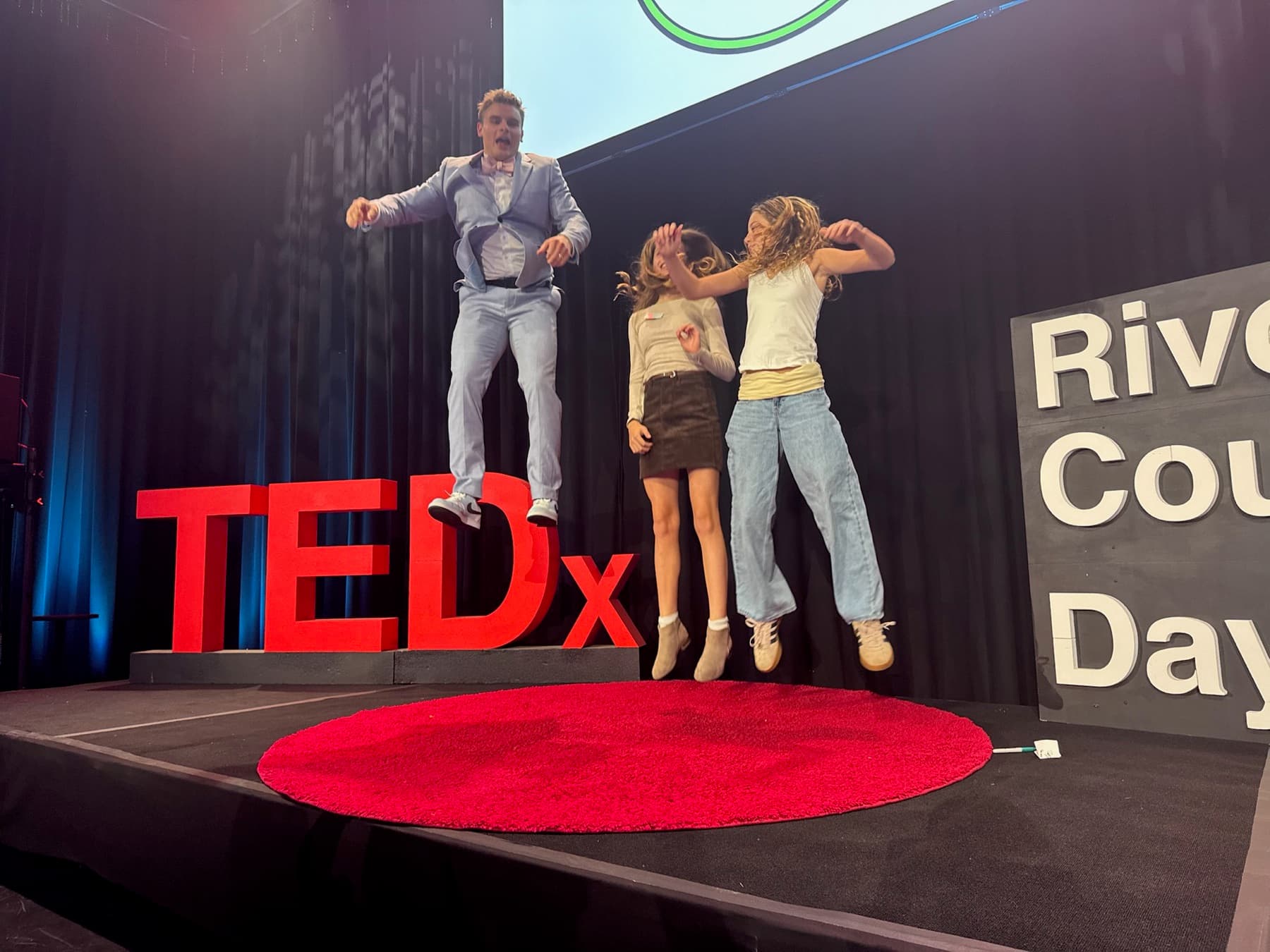 Nate Roy jumping with students on the TEDx stage